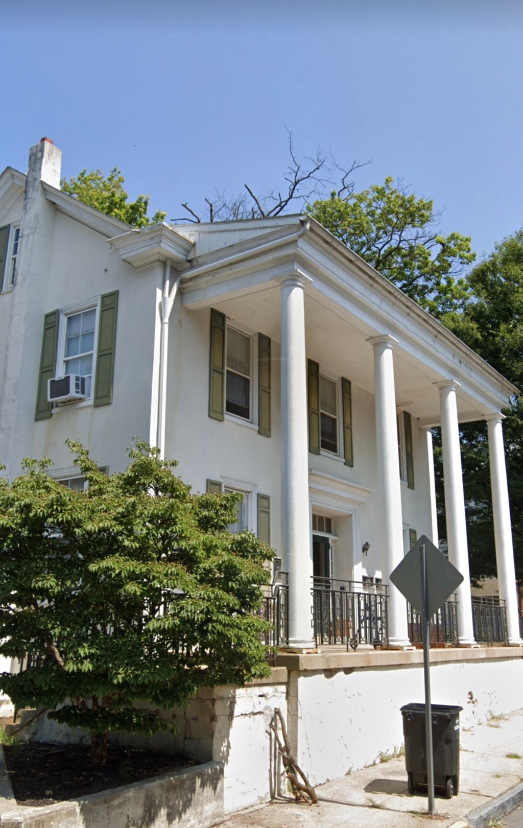 a white house with columns and a street sign in front of it