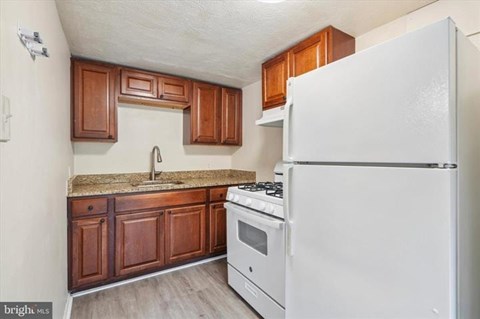 A kitchen with a white fridge, stove and wooden cabinets.