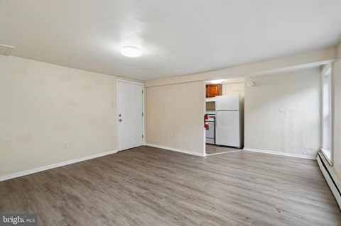 A spacious room with a white door and a white refrigerator.