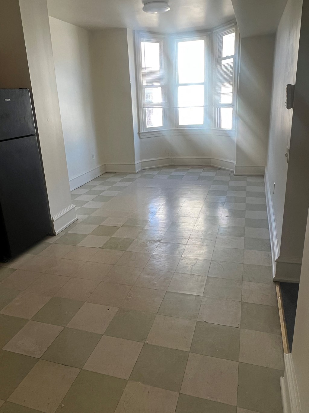 an empty living room with a tiled floor and a window