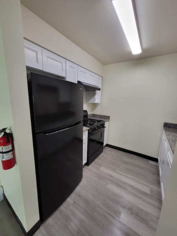 a kitchen with a black refrigerator and a stove