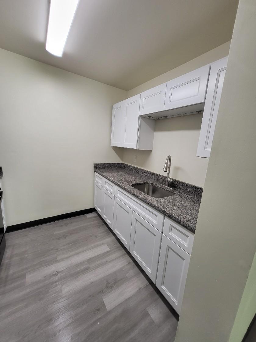 an empty kitchen with white cabinets and a sink