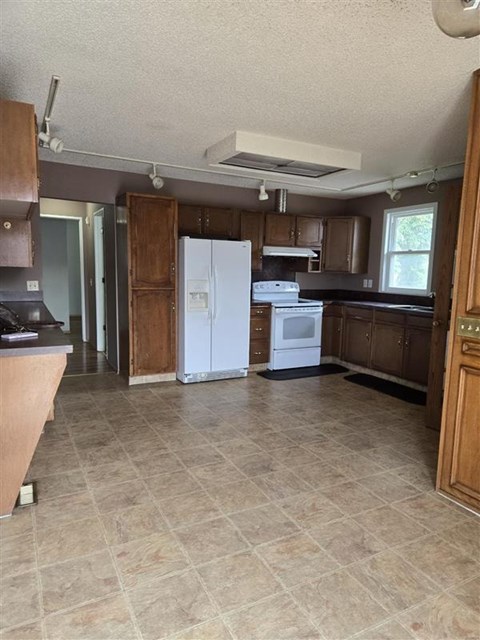 A kitchen with a white refrigerator and wooden cabinets.