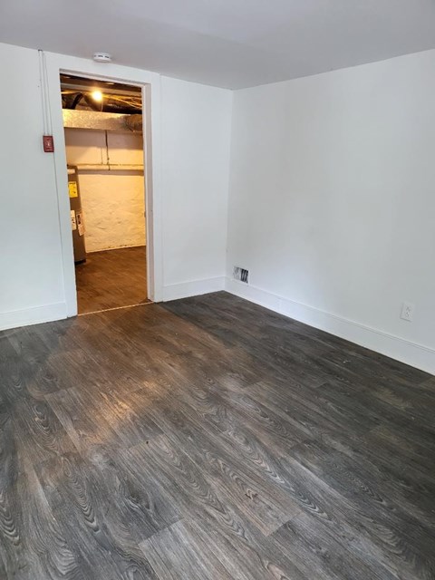 a living room with a wood floor and a door to a bedroom