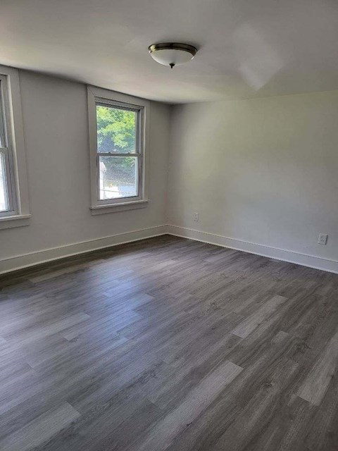 an empty living room with wood floors and a window