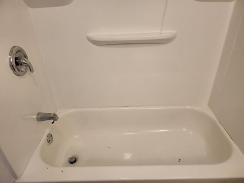 a white bath tub with a shelf above it