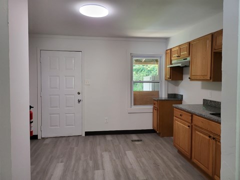 an empty kitchen with wooden cabinets and a white door