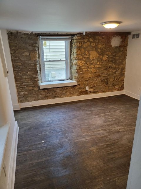 an empty room with a stone wall and a window