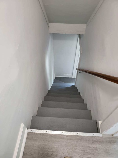 a flight of stairs with white walls and a wooden railing