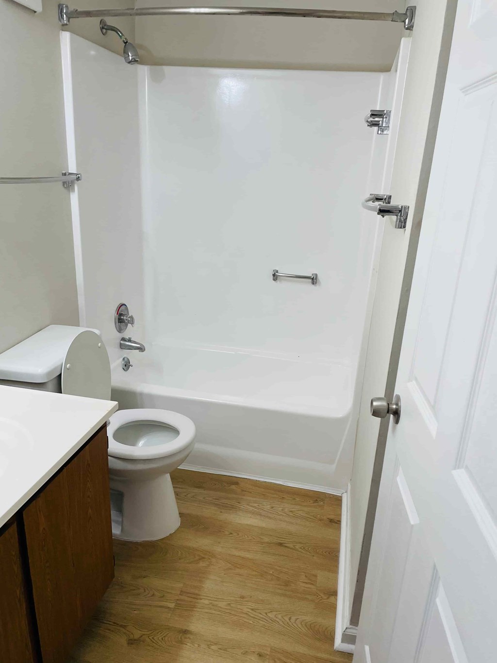 A white toilet sits next to a white bathtub in a small bathroom.