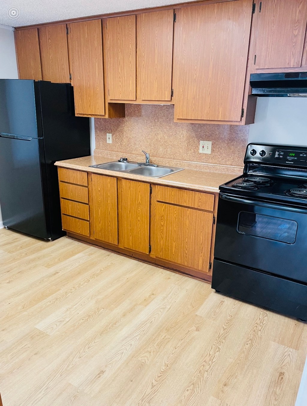 A kitchen with wooden cabinets and black appliances.