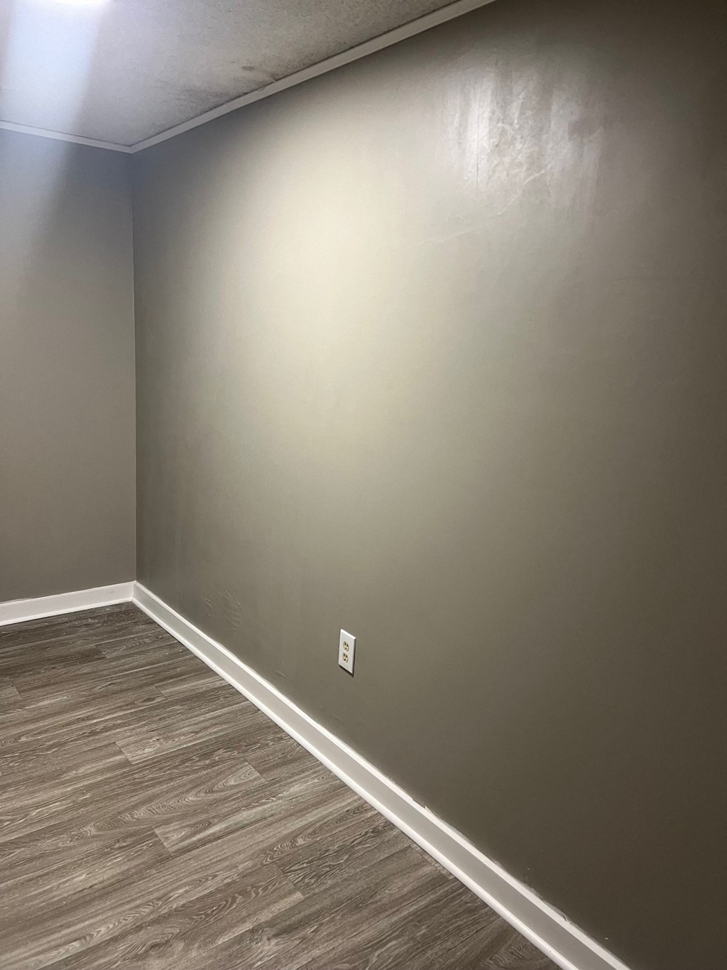 A room with a light grey wall and a wooden floor.