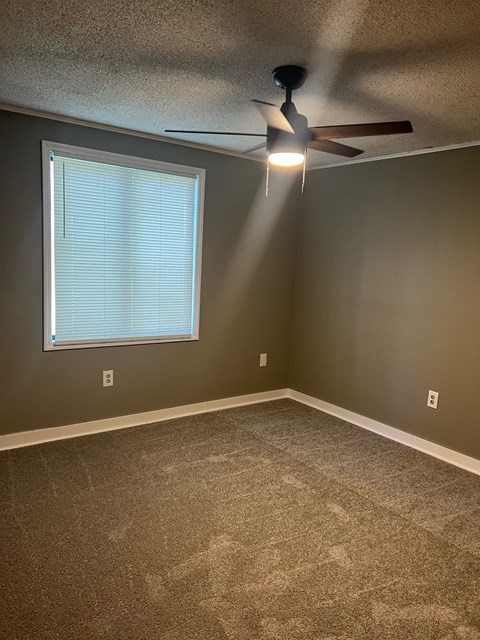 A room with a ceiling fan and a window with blinds.