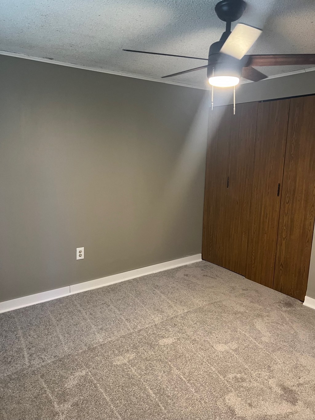 A room with a ceiling fan and a light fixture.
