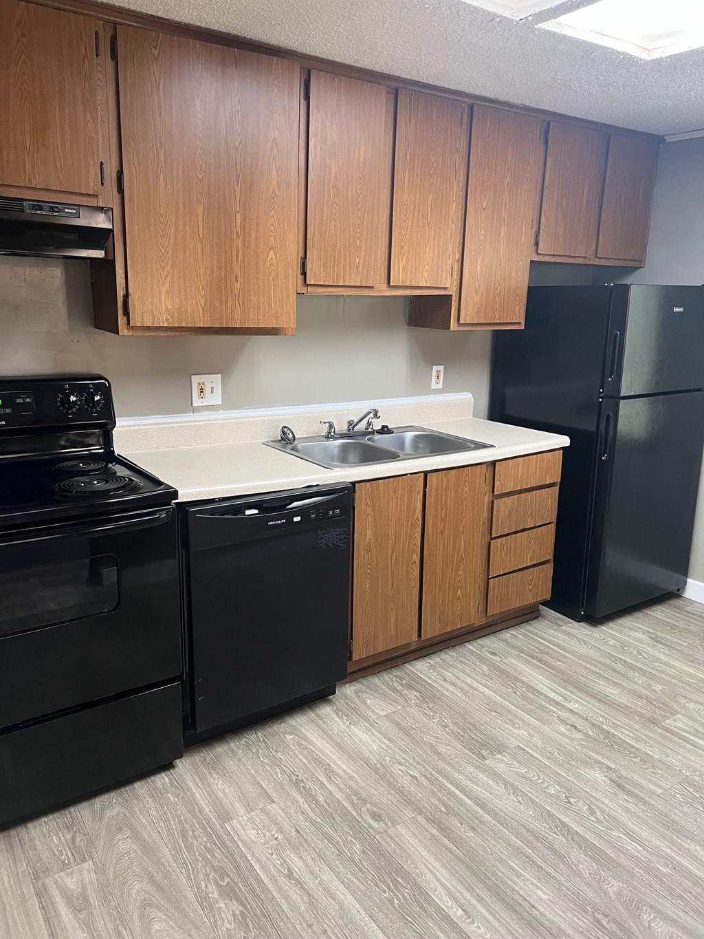 A kitchen with black appliances and wooden cabinets.
