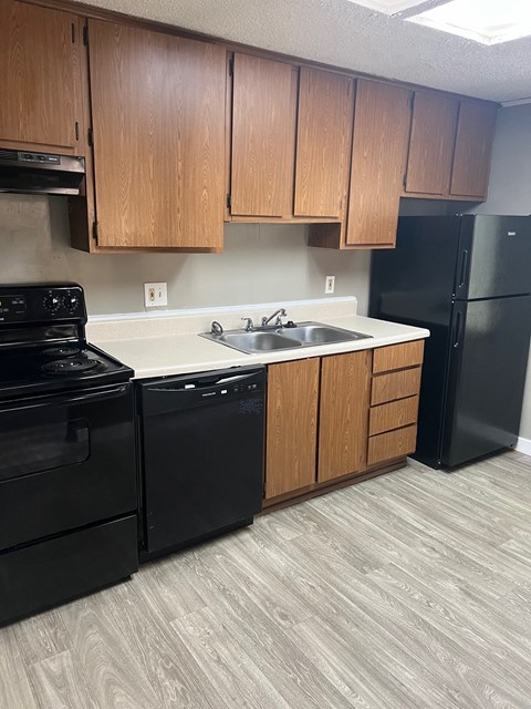 A kitchen with black appliances and wooden cabinets.