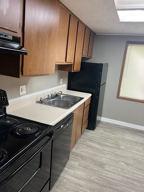 A kitchen with a black refrigerator and a black stove top oven.