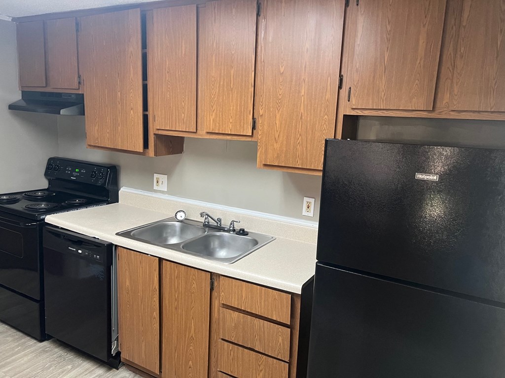 A kitchen with black appliances and wooden cabinets.