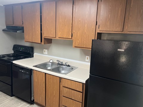 A kitchen with black appliances and wooden cabinets.