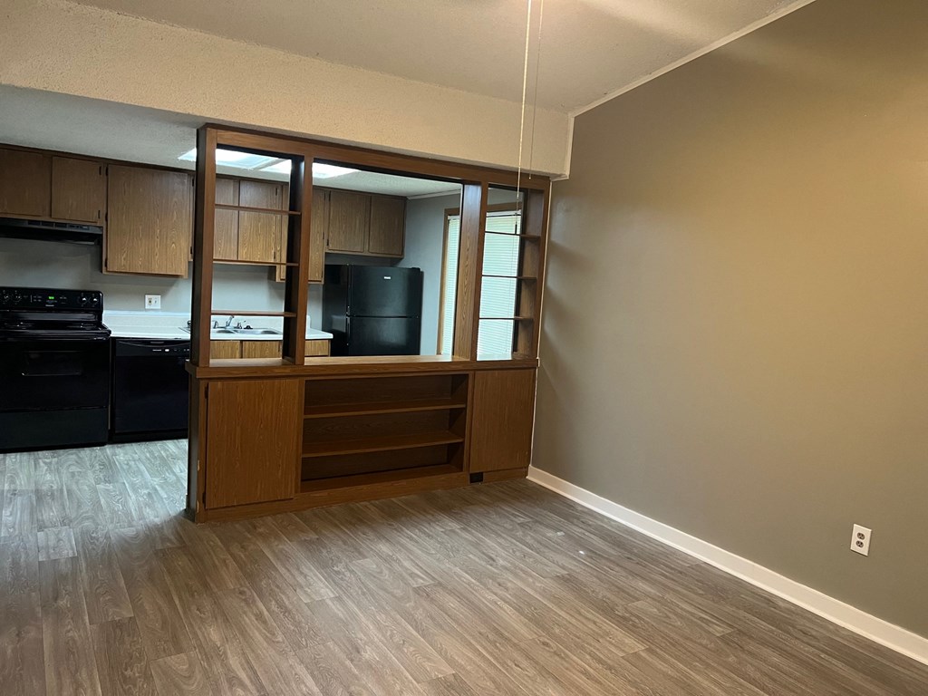 A kitchen with a black refrigerator and wooden cabinets.