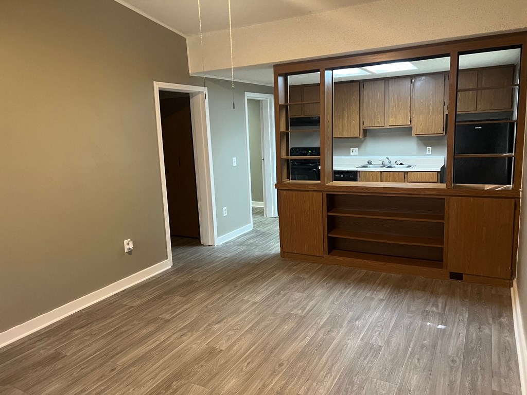 A kitchen with wooden cabinets and a countertop is visible through a glass door.