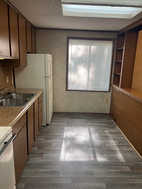 A kitchen with a white refrigerator and wooden cabinets.