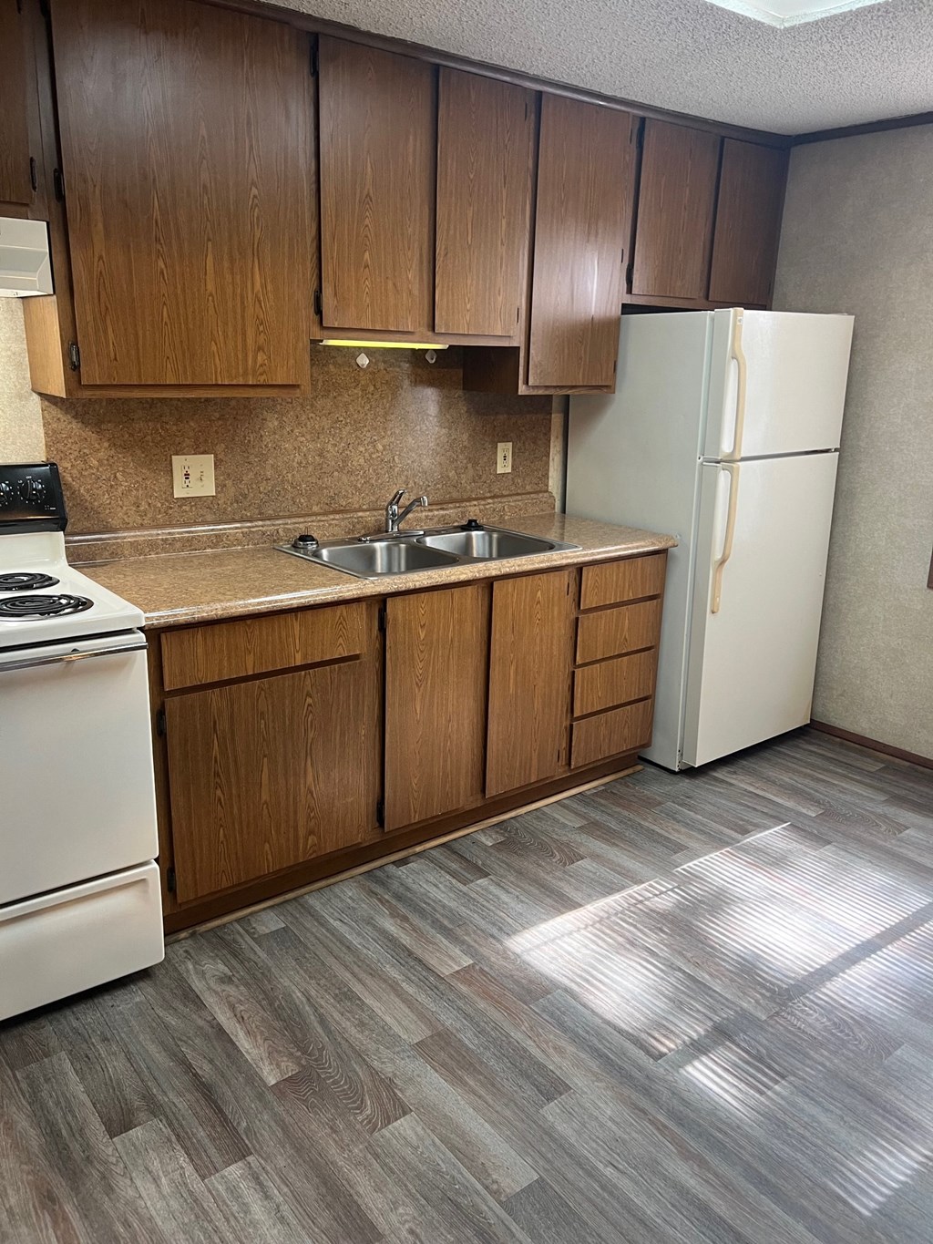 A kitchen with a white refrigerator and wooden cabinets.