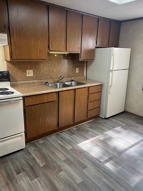 A kitchen with a white refrigerator and wooden cabinets.
