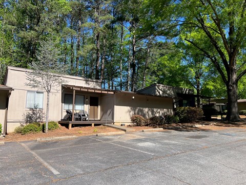 A parking lot in front of a building with trees in the background.