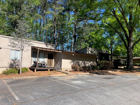 A parking lot in front of a building with trees in the background.