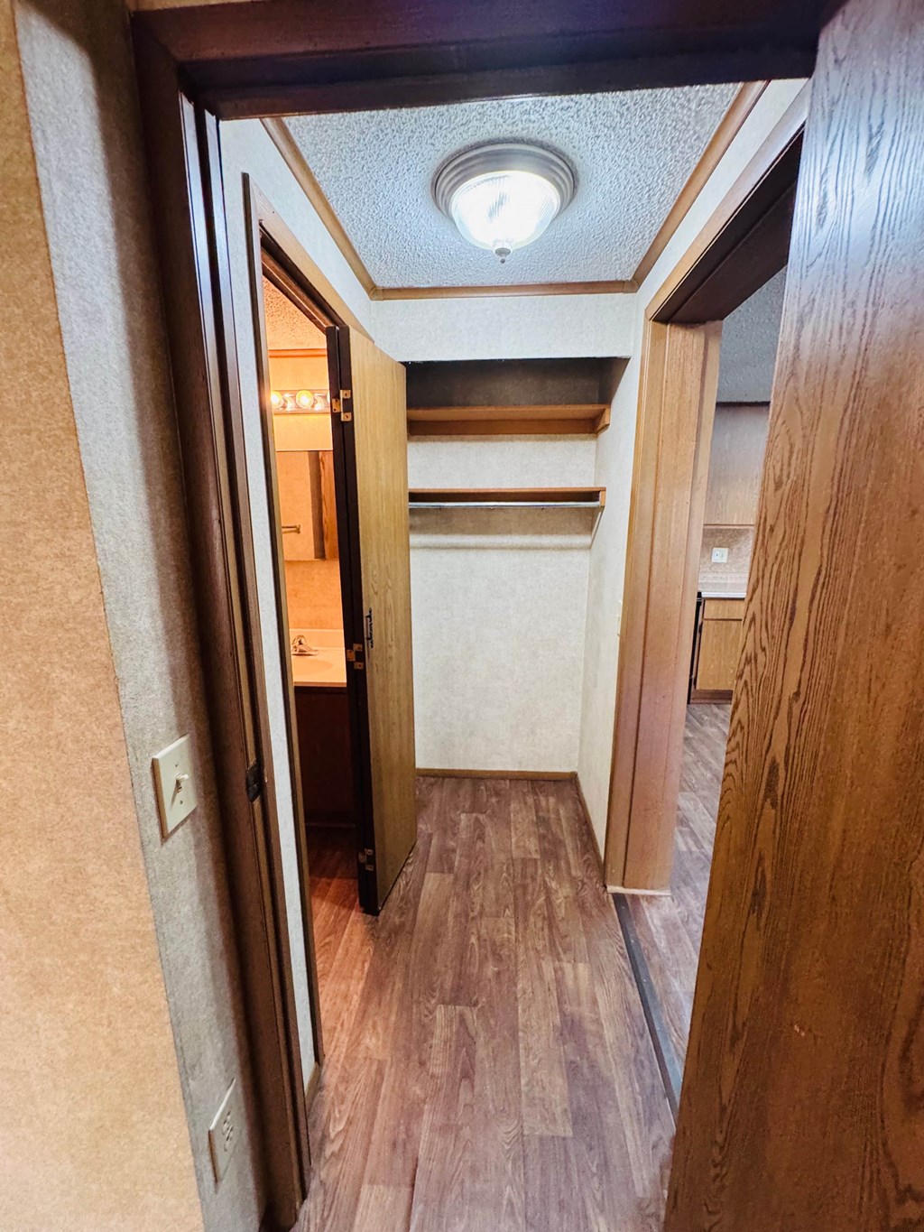 A hallway with a light on the ceiling and a door on the left.