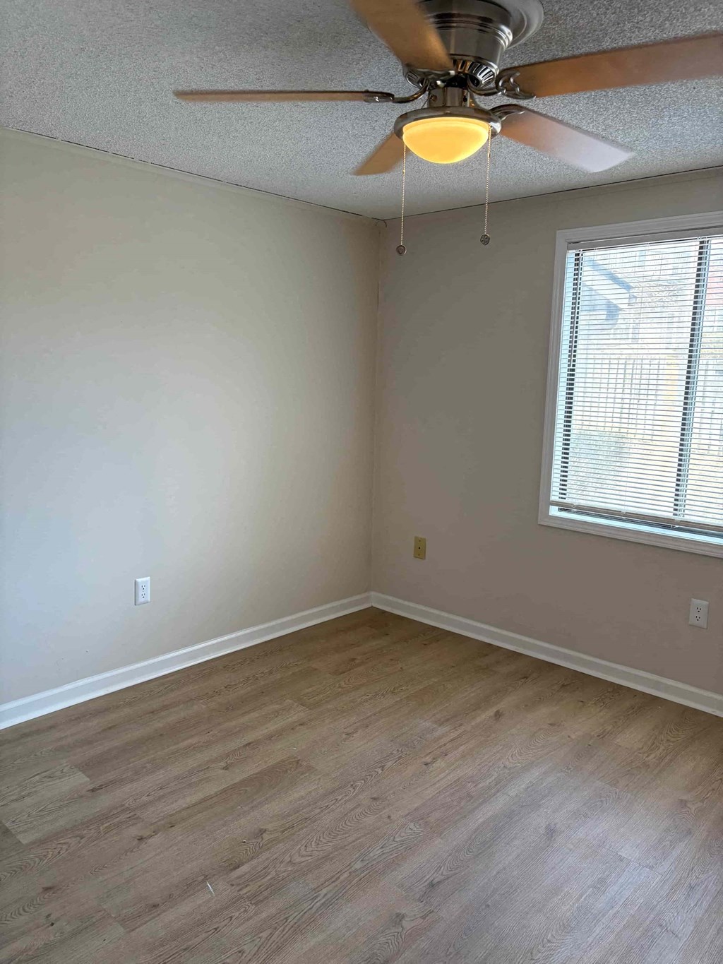 A room with a ceiling fan and a window with blinds.