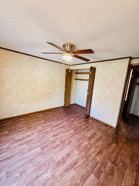 A room with a ceiling fan and wood flooring.