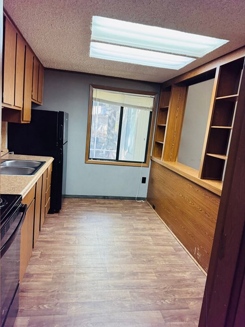 A kitchen with wooden cabinets and a black refrigerator.