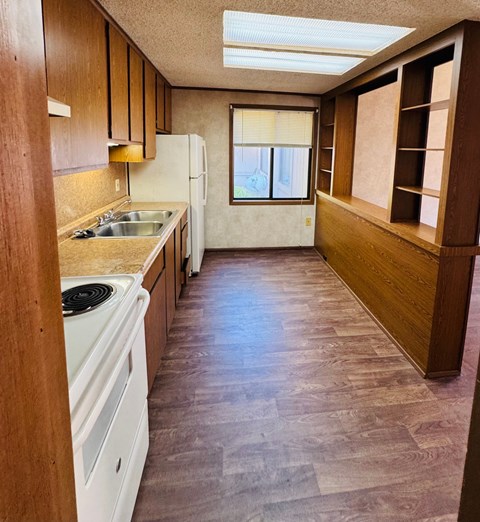 A kitchen with a white dishwasher and a window with blinds.