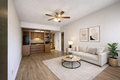 A living room with a white couch, a coffee table, and a ceiling fan.