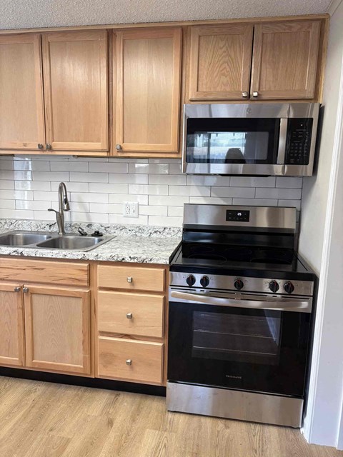 A kitchen with wooden cabinets and a black oven.