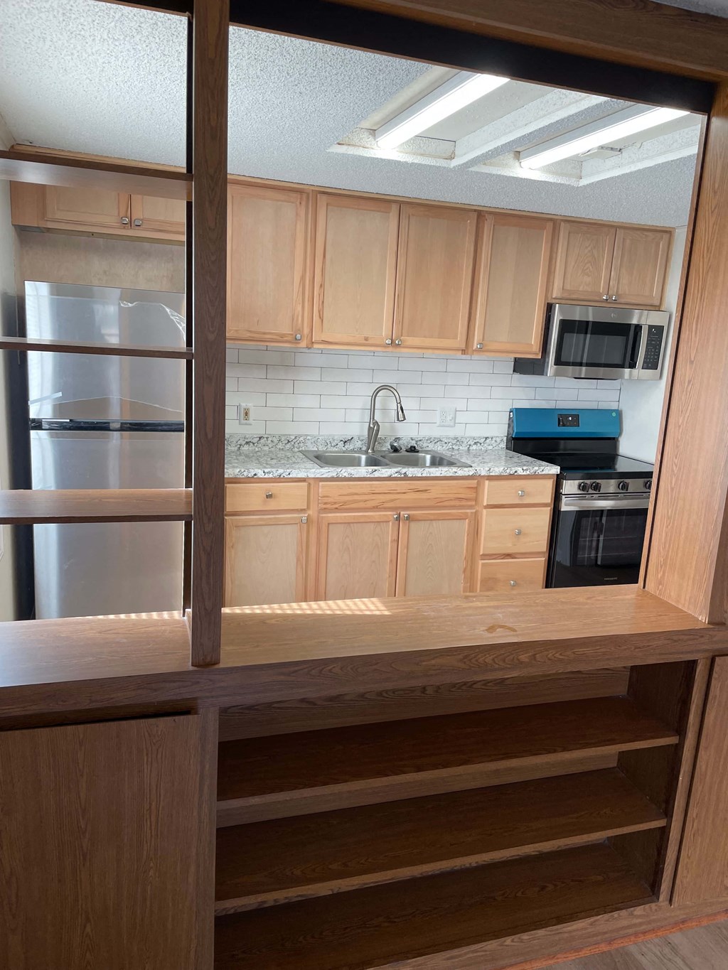 A kitchen with wooden cabinets and a stainless steel refrigerator.