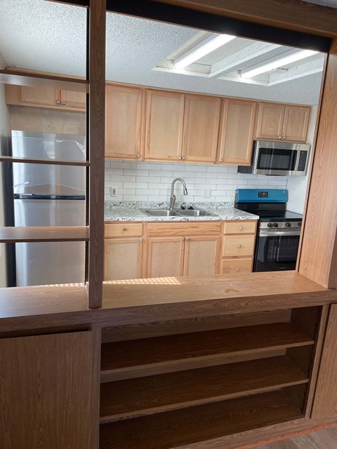 A kitchen with wooden cabinets and a stainless steel refrigerator.