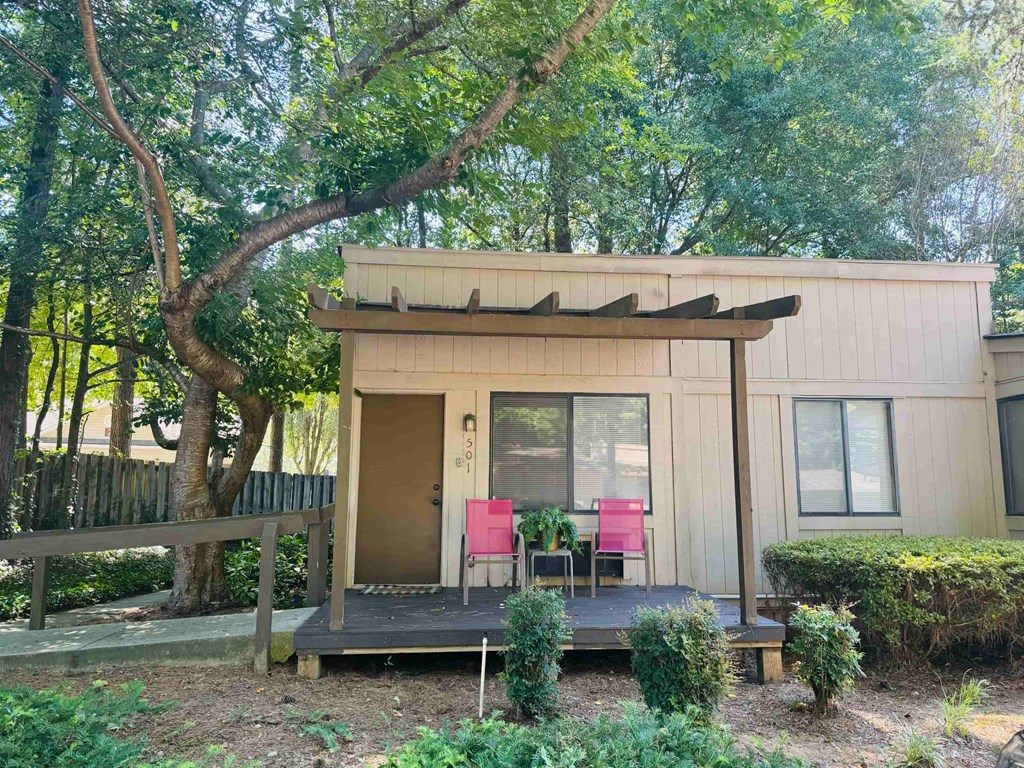 A small house with a porch surrounded by greenery.