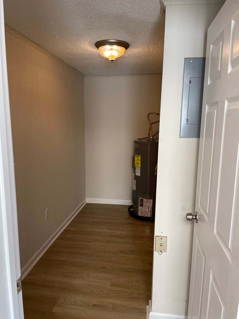 A white door is on the right side of a hallway with a light on the ceiling.