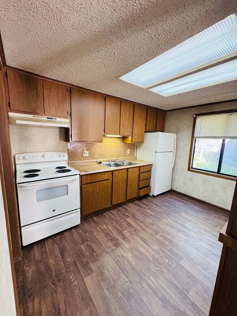 A kitchen with wooden cabinets and a white stove top oven.