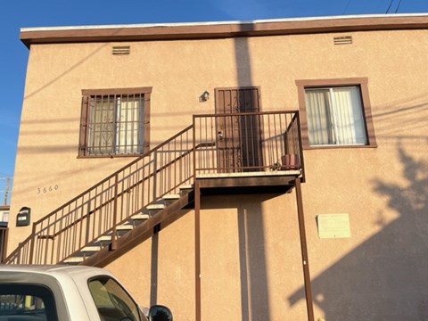 A tan building with a black metal staircase.