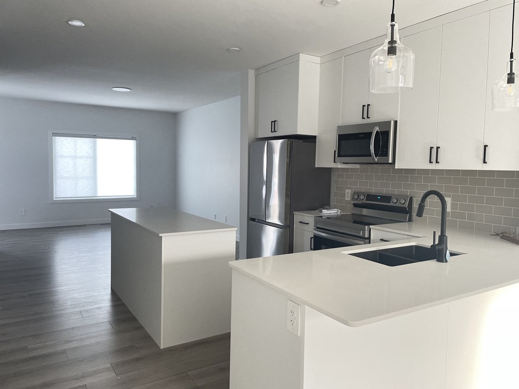 an updated kitchen with white cabinets and stainless steel appliances