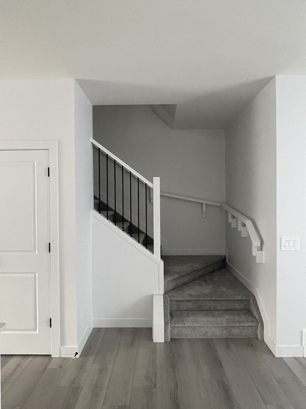 a stairwell in a white house with a white door and a white staircase