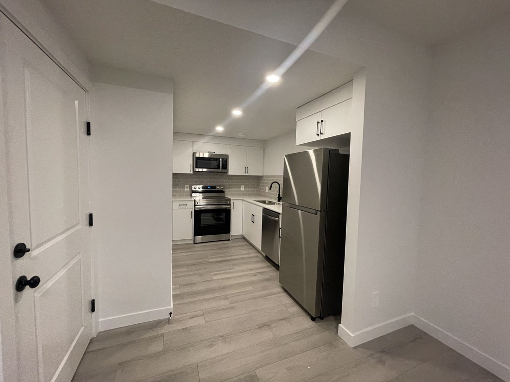 a renovated kitchen with white cabinets and a stainless steel refrigerator