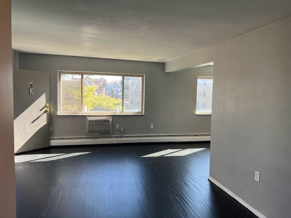 the living room of an empty house with black floors and a window