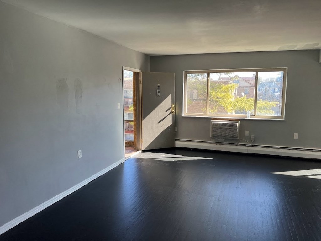 an empty living room with a large window and dark wood floors