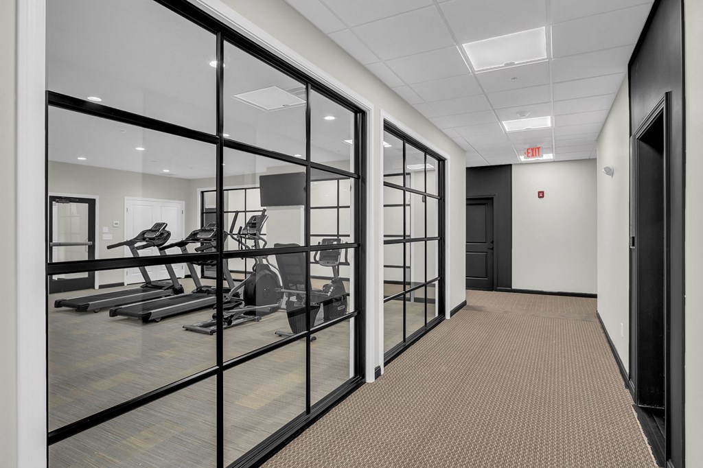 a fitness room with glass doors and a treadmill and weights room