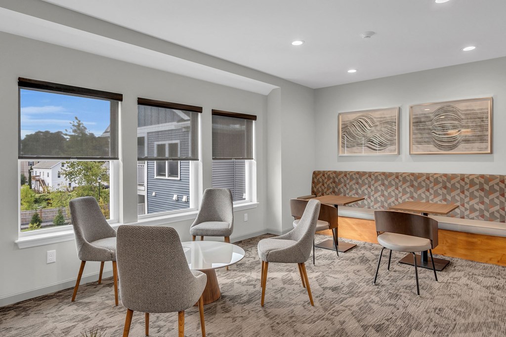 a living room with chairs and tables and a window